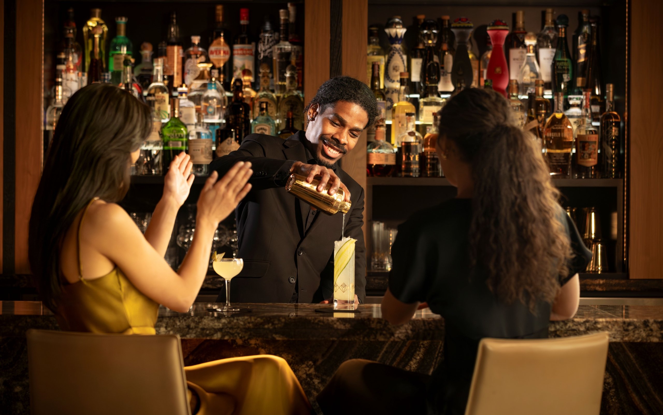 women enjoying cocktails being poured at speakeasy bar