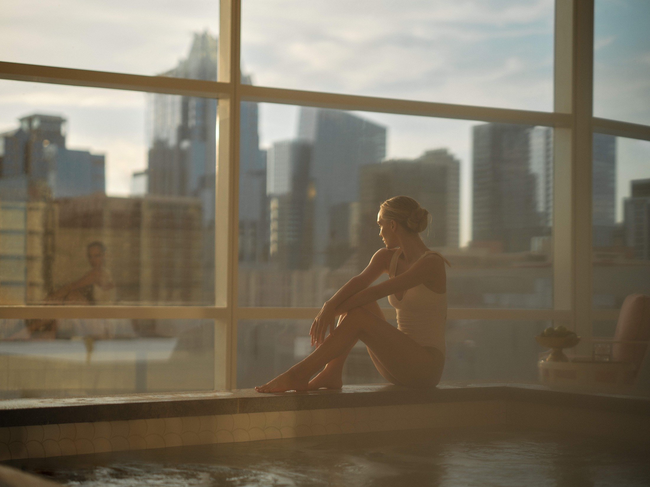 Woman sitting next to window and pool